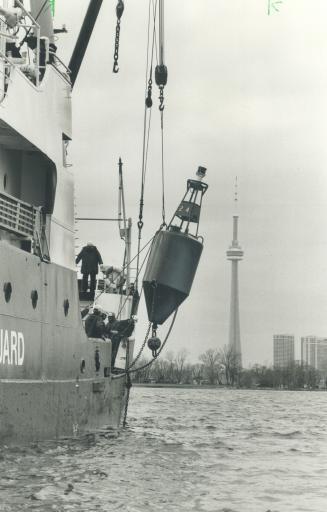 Image shows a buoy being lowered from the ship with the CN Tower in the background.