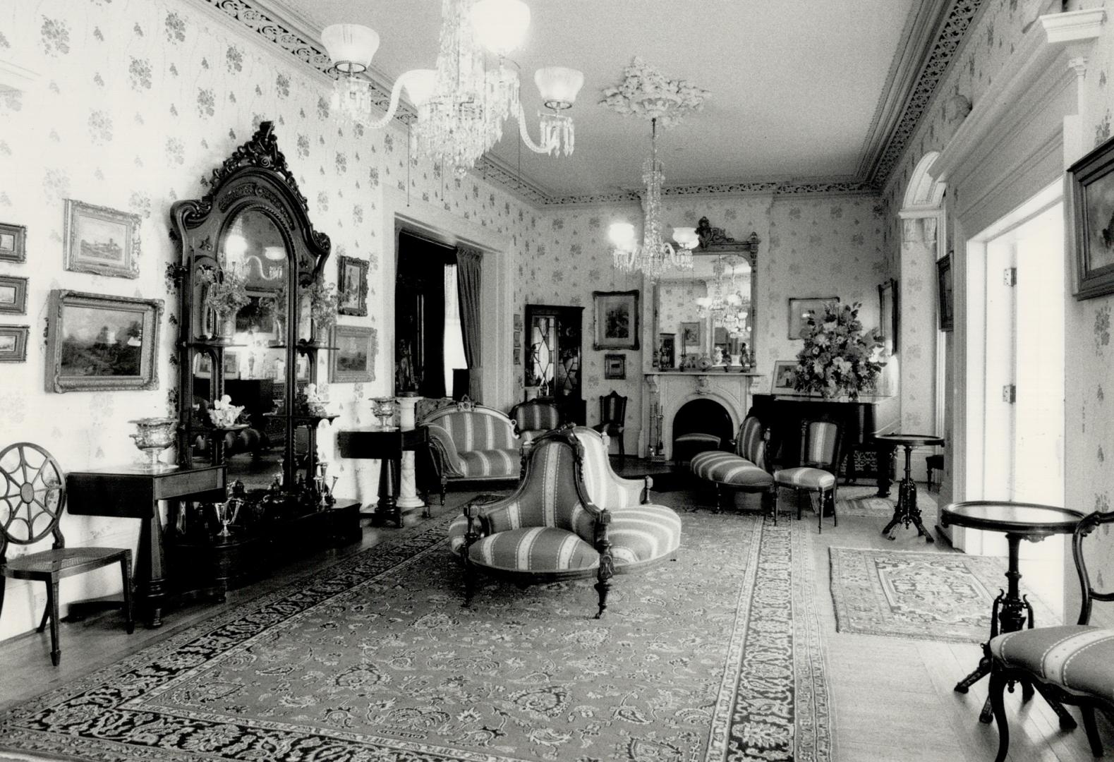 Sitting-room outfitted with wall-mounted art, two large crystal chandeliers, upholstered settee ...