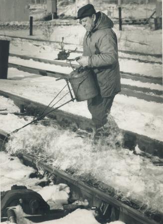 Warming to the job. Worker Joe Dutra helps keep the trains running during the cold spell by pouring a flammable liquid over the rail switches and igni(...)
