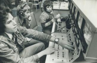 At the control panel operating the television equipment at Station LTPF (Learning Television Production Firsthand), three students cope with problems (...)