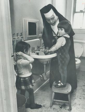 Sister Mary Agnes steers two 3-year-oldsm Jamie, left, and Susie, through their comb-up and freshen-up routine at the Catholic Settlement House Day Nu(...)