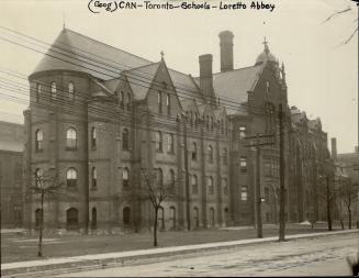 Exterior of four-storey brick building with lancet style windows, steeply pitched roof, dormer …
