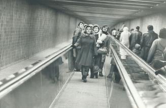 Moving sidewalk on new subway, above, is help to the physically handicaped, reader points out