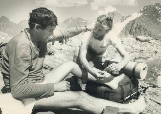 International first aid: Dr Graeme Magor of Hamilton bandages the foot of Soviet explorer Dmitri Shparo after a gruelling climb in the mountains of Soviet Kazakhstan