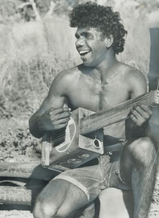 Native strumming a home-made guitar is descended from the original inhabitants of Australia, the aborigines