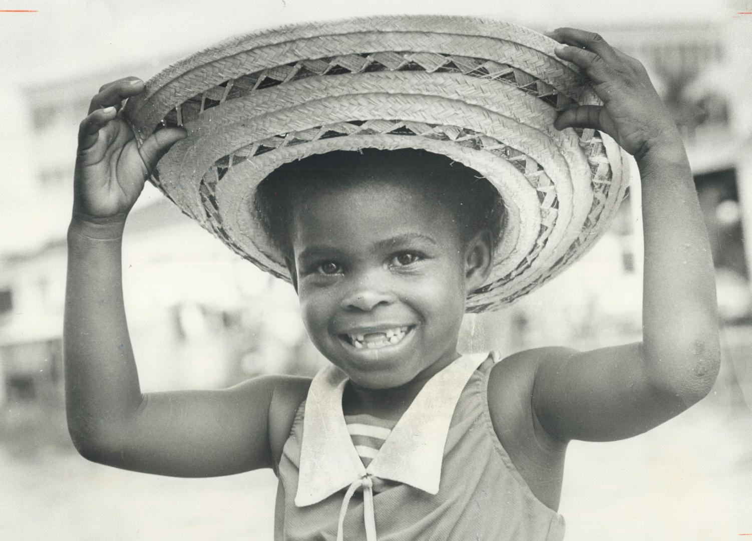 A wide if gap-toothed grin is bestowed by Bahamian child, above