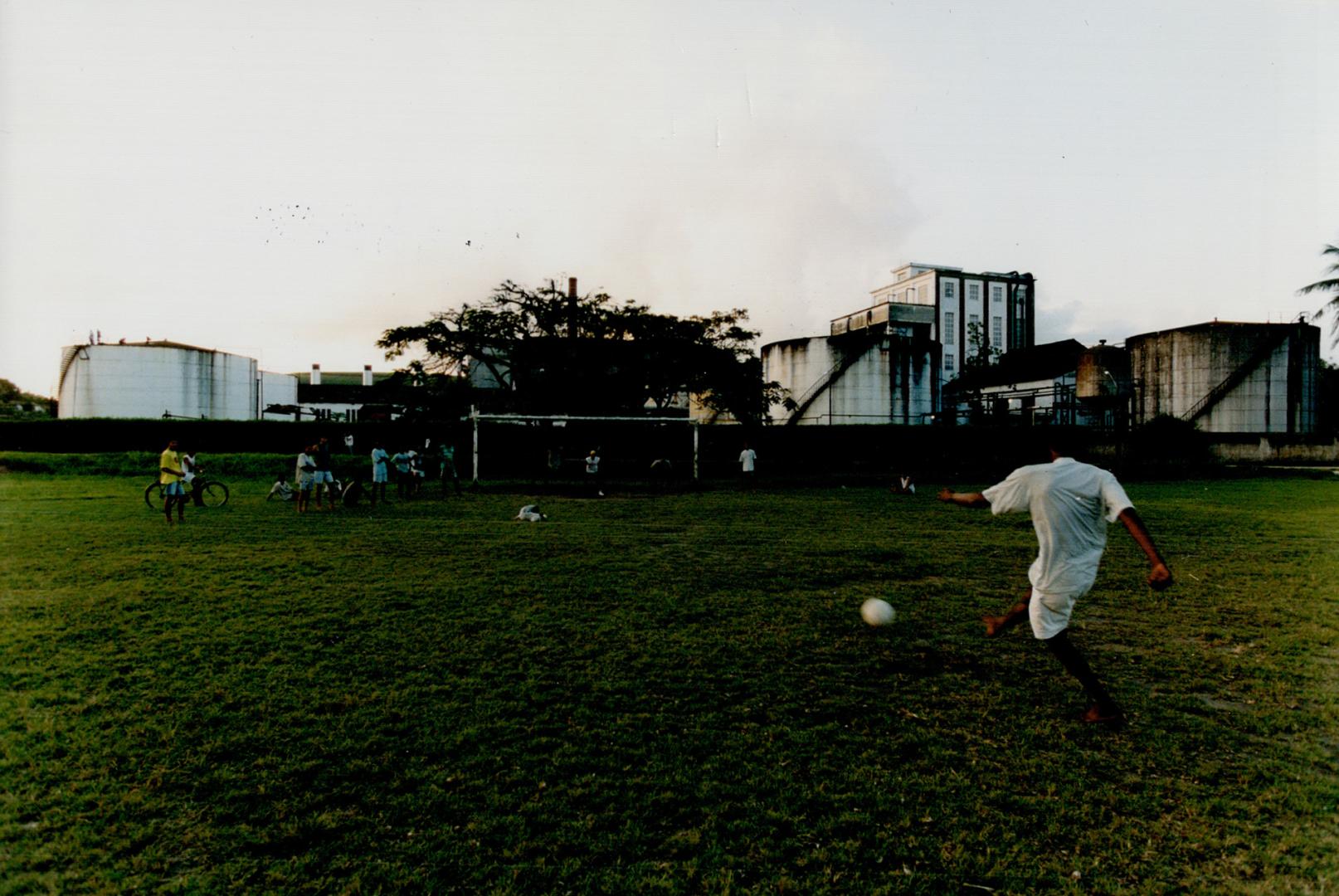 Youth playing soccer near a sugar cane plantation