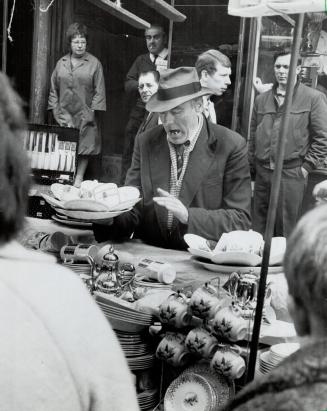 London flea market merchant is caught in mid-spiel as he peddles crockery in Petticoat Lane