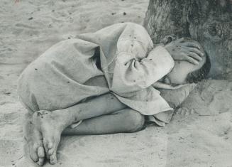 A tuareg orphan, his parents dead in last year's drought, lies on the ground in the refugee camp