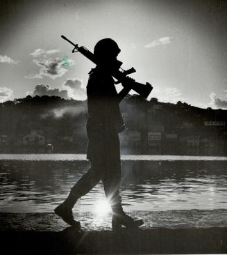 On guard: A U.S. marine patrols the waterfront in downtown St. George's Grenada, at sunrise last november, after the marines invaded the tiny Caribbea(...)