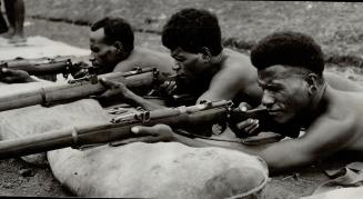 Brawny Papuan infantrymen draw a bead on distant targets as they practise rifle shooting in their native New Guinea