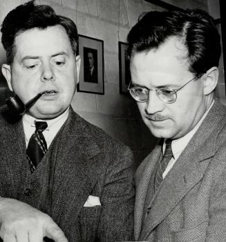 Ernest MacMillan, conductor of the Toronto Symphony Orchestra, and Charles Peaker, conductor of the huge choir, examine the score of a number