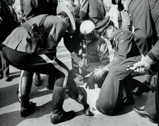 Pinned to the ground by RCMP and security police, leather-jacketed man shouts into a reporter's microphone after attack on Soviet Premier Alexei Kosygin