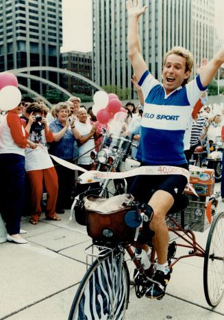 Triumphant return: Richard Beecroft jubilantly wheels across the finish line at Nathan Phillips Square as a crowd of well-wishers welcome him back from his global cycling odyssey