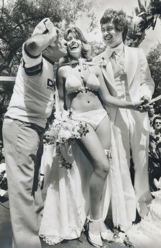 Johnny Lombardi, who masterminded International picnic, kisses bikini-clad bride Yolanda Margareta as husband Christopher Kayser looks on. Reader objects to the wedding as stupidity