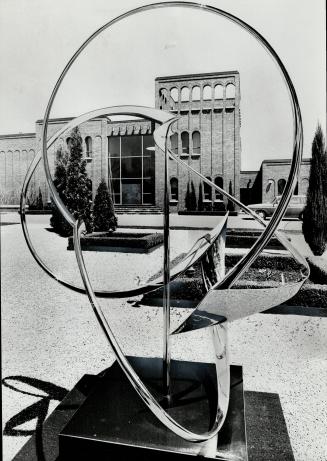 Striking front exterior of the house is seen through a piece of reflecting sculpture in formal garden