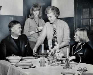 Rev. Harold Neal Burgess and his wife having dinner with their children. Doing the serving is 19-year-old daughter Elizabeth. Joan (right) is 14