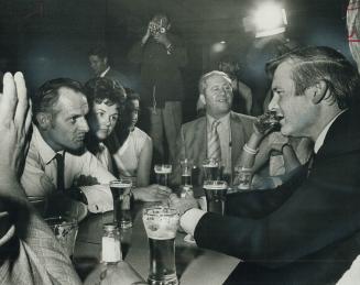 With a glass of beer in front of him, Premier William Davis listens to Bill Brown, president of the Sudbury and District Labor Council, at the Steelwo(...)