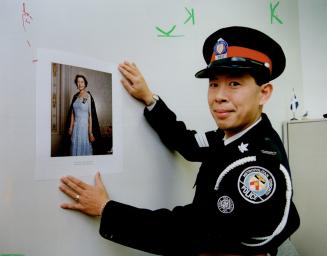 Royalty loyalty: Metro police Sergeant Benny Eng, pictured with a new photo of the Queen at police headquarters, says he had no difficulty swearing aliegiance to the Queen when he joined the force