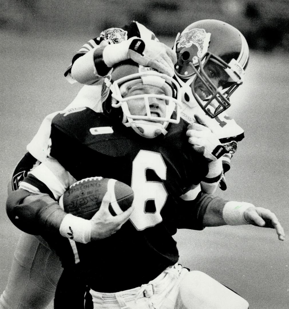 Three TDs for rookie: Argo rookie tailback Gill Fenerty is collared by Ticat cornerback Less Browne (above) but eludes this swarm of tacklers (right) to score one of his three TDs on the afternoon