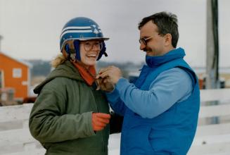 Trainer Jeff Ginn helps Fish strap up her helmet, at top