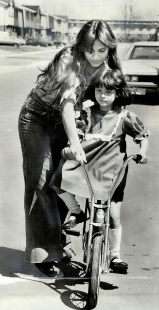Florence Field, 9, gets a hand from her new sister, Mary-Ann, 13, as she learns to ride a bike at her new home