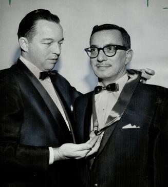 Install Phil stone. J. J. Fitzgibbons Jr., Variety clubs International representative, places insignia on Phil Stone, elected Chief Barker of Ontario's Tent 28 for 1961