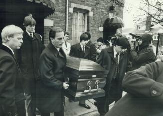 Pallbearers carry the coffin while mourners Vince Alexander and Frank Volpe talk together at cemetery