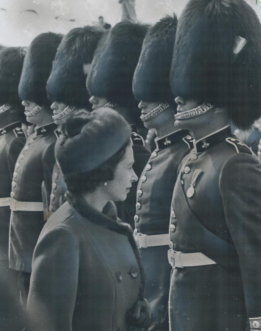 Stiffly at attention stand members of the red-coated honor guard of Grenadiers as they are inspected by Queen Elizabeth