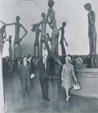 The Queen is dwarfed by tall statues called Britain in the World as she toured the British pavilion at Expo today