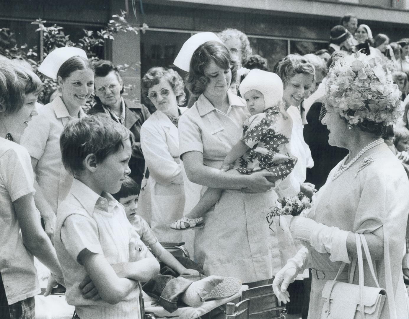 A Royal greeting for small patients: Wearing a lime green dress and matching hat, the Queen Mother greets crowd of nurses and patients out side Hospital for Sick Children today