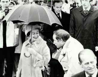 Care to share my Umbrella? The Queen appears to be asking Prime Minister Pierre Trudeau during Parliament Hill church services Sunday on front lawn. T(...)