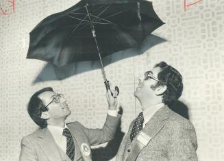 Ontario Consumer Affairs Minister Larry Grossman (left) acts out his proposed new ''umbrella'' franchising legislation for Marvin Goldberg, president (...)