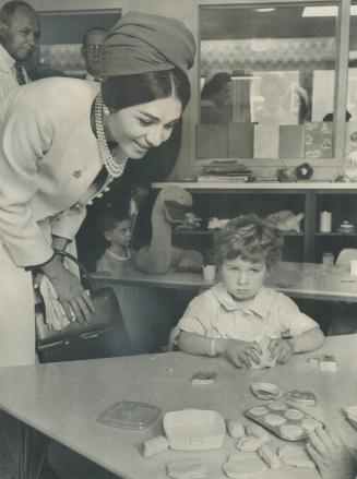Saying hello to youngsters at the Hospital for Sick Children, Empress Farah bent over to give a special royal smile to this tiny patient. [incomplete]