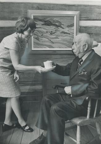 Artist A. Y. Jackson accepts a cup of coffee from Gladys Ireland. Visitors to the gallery can often see the artist-in-residence sitting in a rocking c(...)