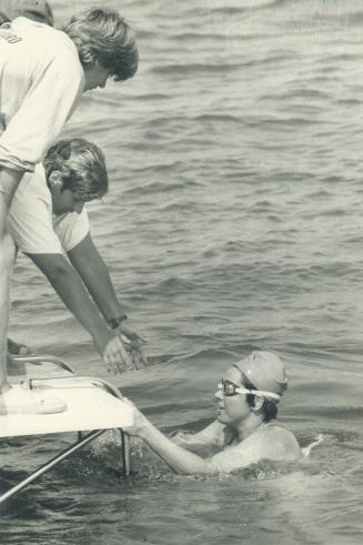 Image shows a long-distance swimmer climbing aboard after finishing lake Ontario crossing.