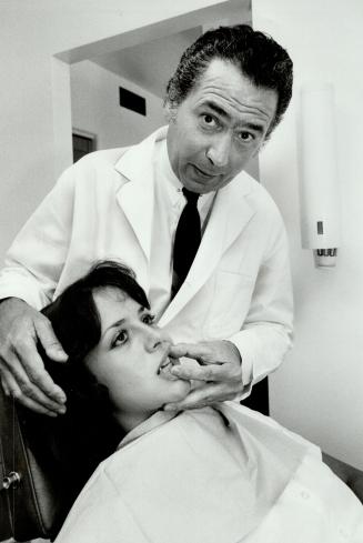 Soon no pain: Dr. Malcolm Yasny inserts a device like a boxer's mouthguard to treat dislocated disc in jaw of Linda Gramolini, 20