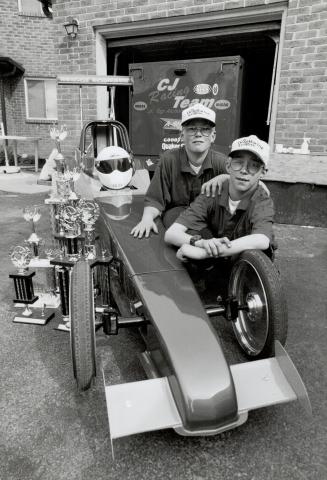 Young speedsters: Craig, left, and Jason Huestis show off their 12-foot junior dragster and trophies they have won by lapping the field at drag races here and south of the border