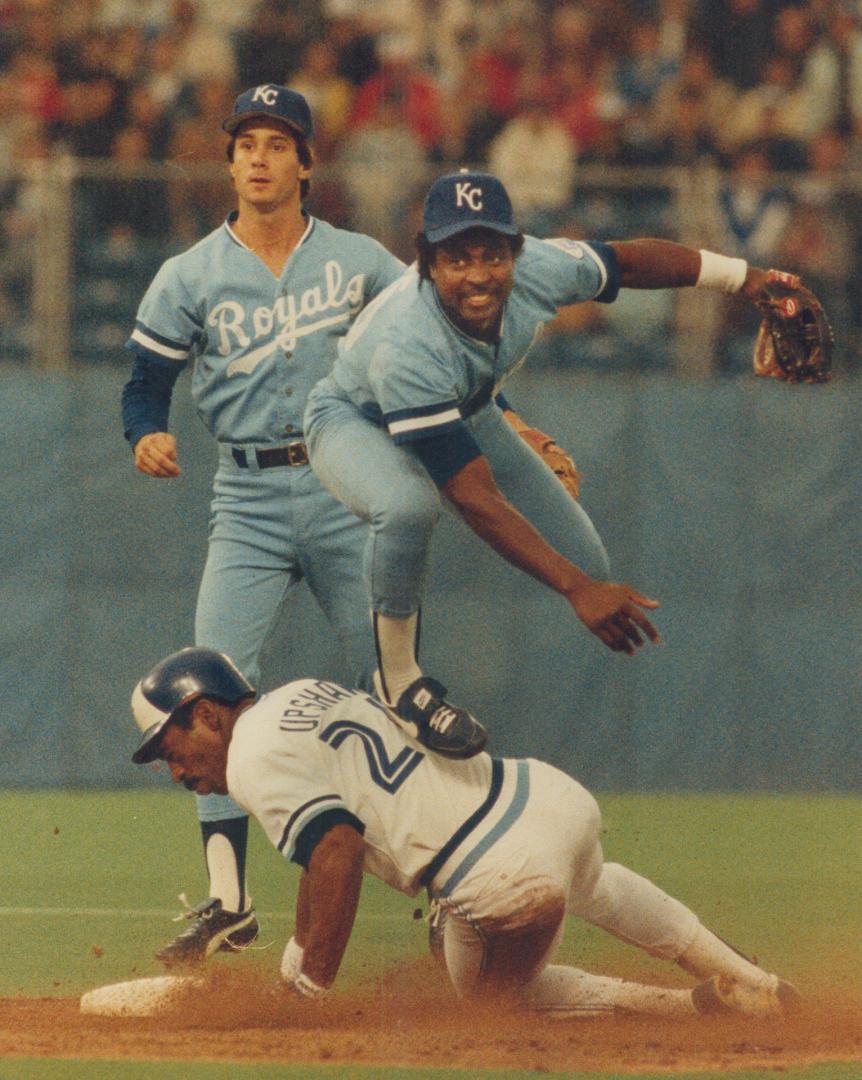 Right, Frank WHite of Royals leaps over Willie Upshaw at second, but was late with throw to first [Incomplete]