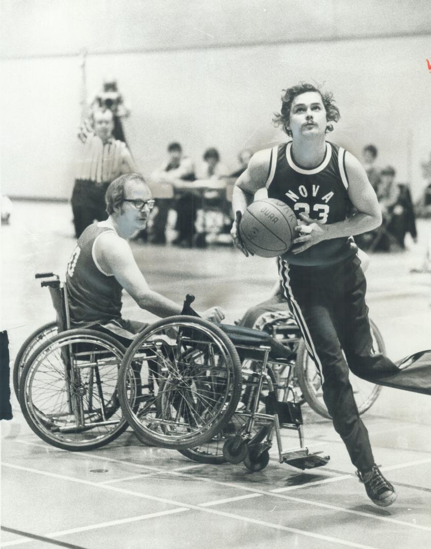 Collision on the court. Dave Morehouse of Nova Scotia hops on one leg to attempt to score after he was involved in collision in Canadian wheelchair ba(...)