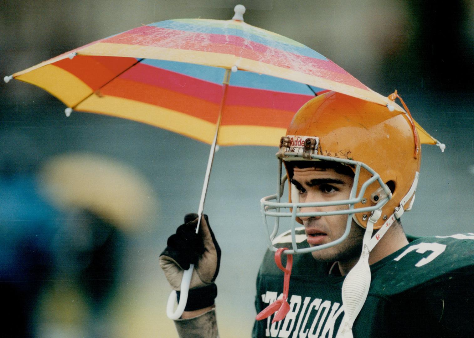 Rain, rain, go away. Paul Jebely, a member of Etobicoke Collegiate Institute's football team, does his best to keep dry during a sudden-death qualifie(...)