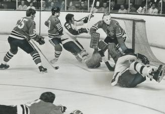 Sliding along on seat of pants is centre Norm Ullman of Maple Leafs, while left winger Errol Thompson (12) tries his best to avoid similar fate as he (...)