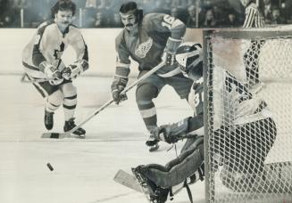 Dunc Wilson, Maple Leafs' goalie, kicks out puck as teammate Jim McKenny and Detroit Red Wings' Henry Boucha both skate towards rebound in last night'(...)
