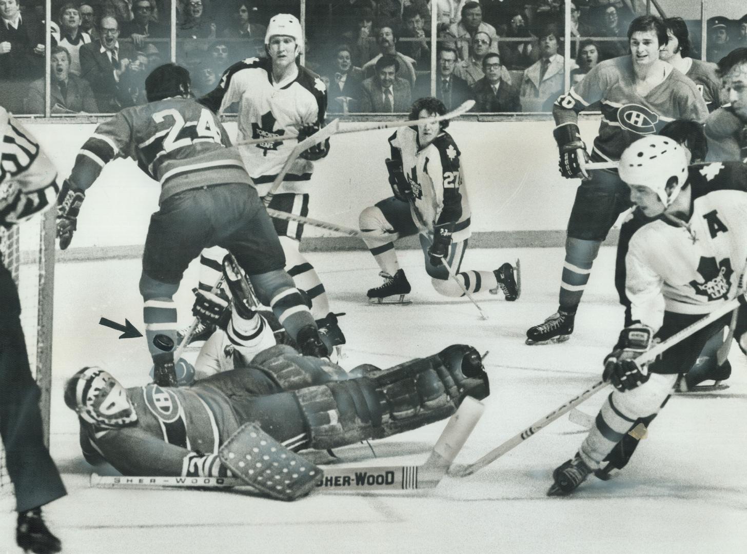 Flat on his back, Montreal Canadiens' goalie Ken Dryden is helpless to prevent puck (see arrow) fired by Leafs' Ron Ellis (right) from entering net wi(...)