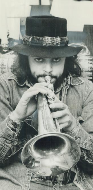 Flugelmeister Chuck Mangione, the 33-year-old composer, symphonic conductor and jazz quartet leader, gives demonstration on prized $400 brass instrume(...)