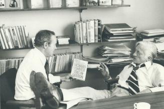 Publisher Jack McClelland (feet on desk) and author Richard Rohmer, in McClelland's office