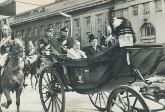 To Queen's Park, Lietenant-Governor Pauline McGibbon and her husband sit in an open landau escorted by the Gov-general's Horse Guard. After arriving a(...)