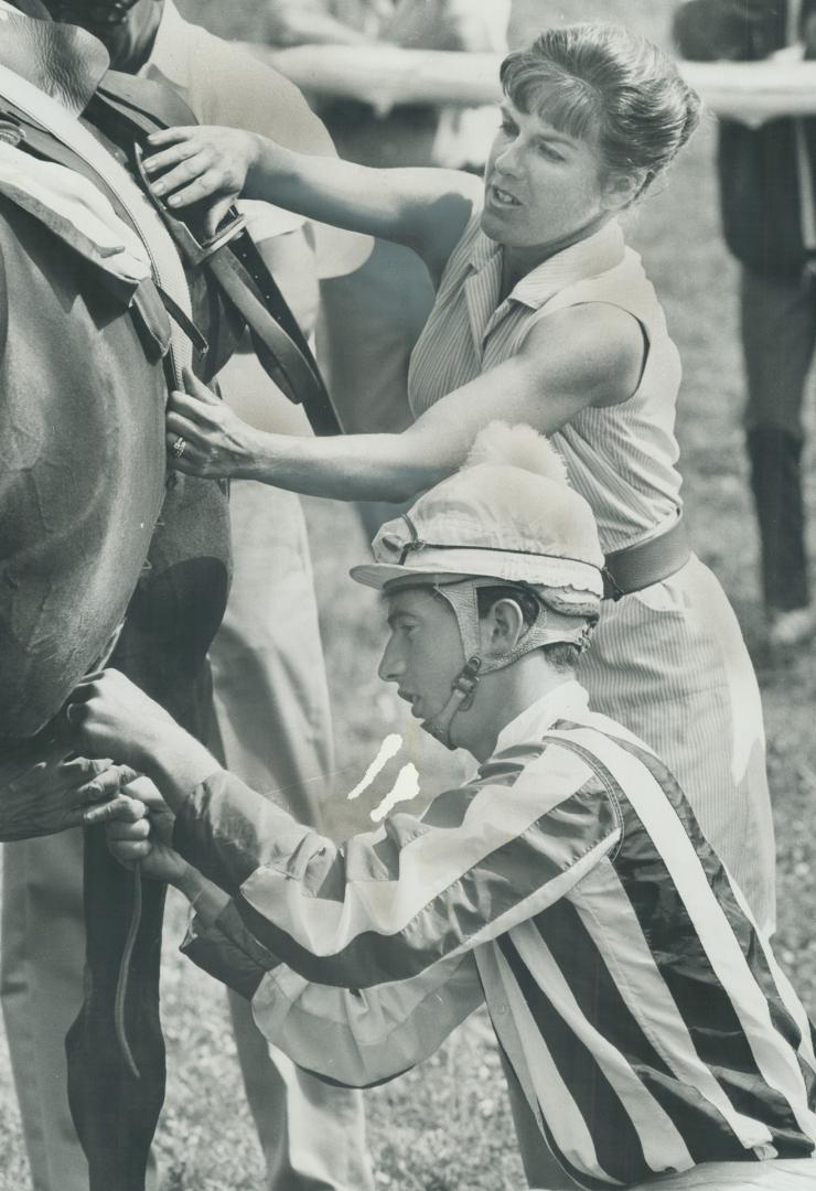 Sally Merrill, wife of trainer Frank Merrill and a conditioner in her own right, helps jockey, Earl Barnett, saddle Botticetto for Foxhunter Plate steeplechase race