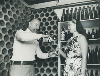 Mr. and Mrs. Miller sample the homemade burgundy. Among artist Miller's enthusiams is the making of his own wines