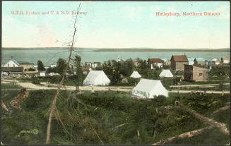 Pictures shows tents erected on a hill beside a lake.